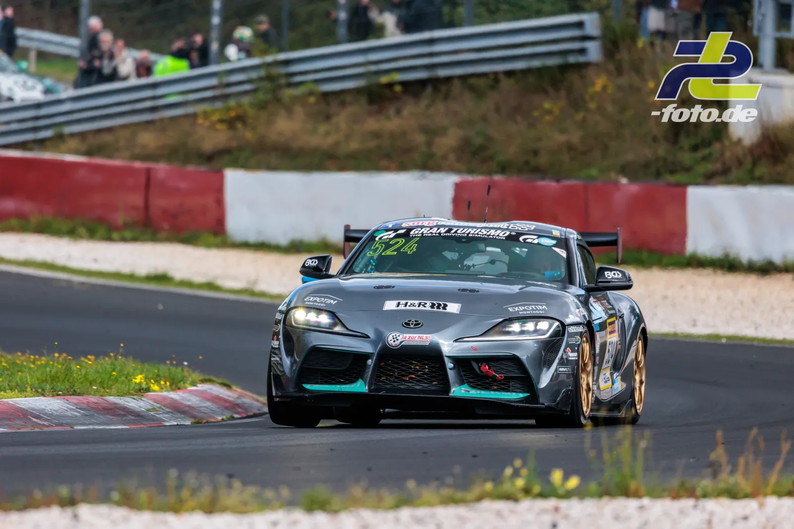 Toyota Supra auf der Nordschleife des Nürburgrings während des NLS-Rennens, bei Kurvenausgang über Randstein fahrend.