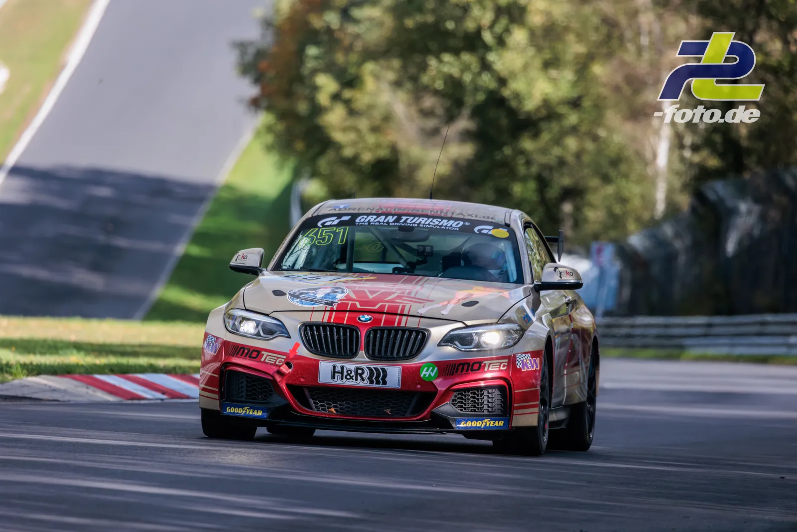 BMW M240i Racing Cup auf der Strecke beim NLS-Rennen am Nürburgring, Frontansicht in einer Kurve mit Randsteinen.
