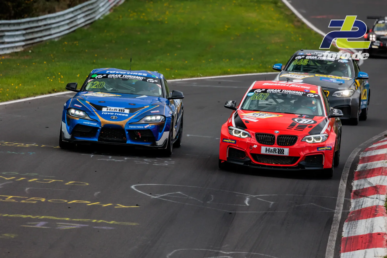BMW M240i Racing Cup #667 im Rennen auf dem Nürburgring, gefolgt von weiteren Fahrzeugen in einer Kurve der Nordschleife.