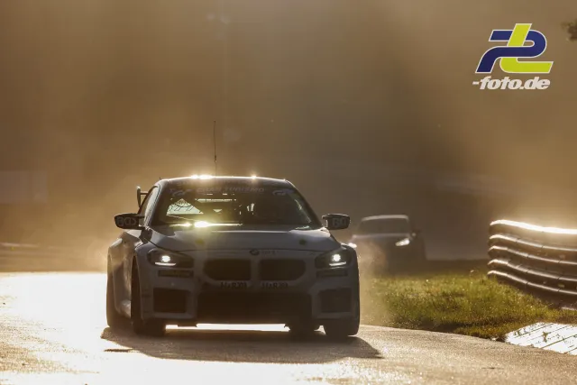 BMW M2 Racing im Gegenlicht auf der Nordschleife, gefolgt von zwei weiteren Fahrzeugen im Dunst