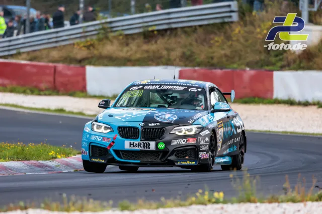 BMW M240i Racing auf der Nürburgring-Nordschleife, Startnummer 650, in einer Kurve mit blau-grauer Lackierung und H&R-Sponsoring.