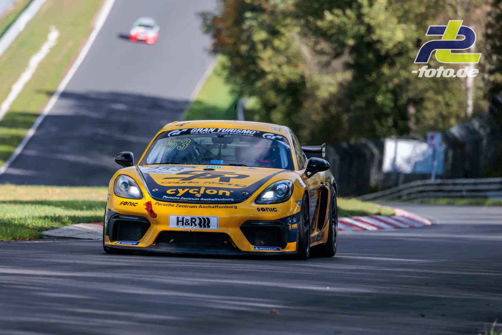 Gelber Porsche Cayman mit cyclon-Sponsoring in Kurve auf der Nordschleife bei NLS-Rennen am Nürburgring.