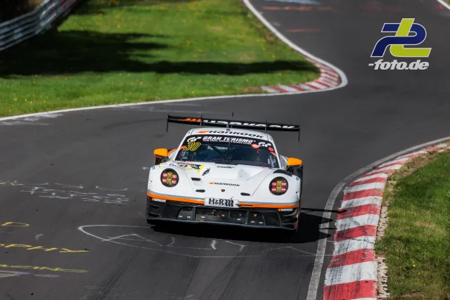 Porsche 911 GT3 R in weiß-oranger Lackierung von vorne auf der Nordschleife während des NLS-Rennens.