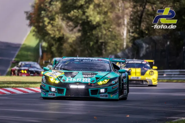 Türkisfarbener Lamborghini gefolgt von gelbem Porsche und weiteren Fahrzeugen auf der Nordschleife beim NLS-Rennen.