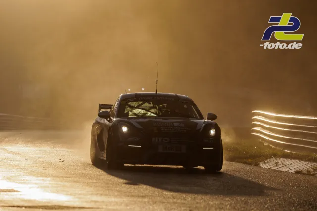 Rennwagen mit eingeschaltetem Licht im starken Gegenlicht bei tiefstehender Sonne auf der Nordschleife.