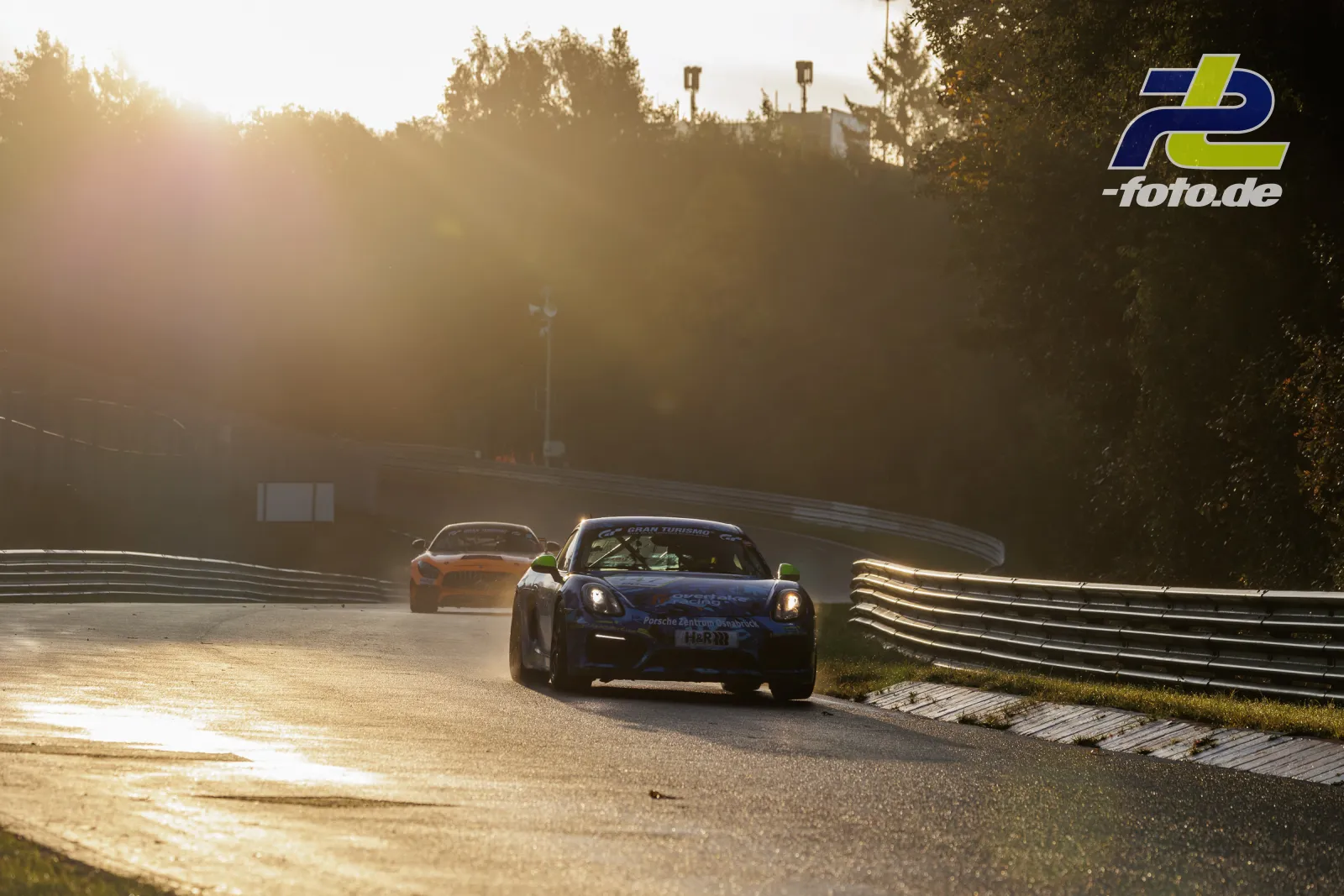 Porsche Cayman auf der Nürburgring-Nordschleife im Qualifying bei Gegenlicht. Im Hintergrund ein weiteres Fahrzeug.
