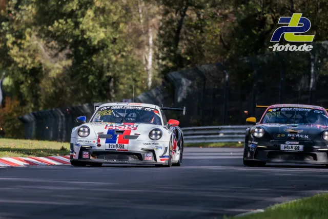 Zwei Porsche 911 GT3 Cup im Duell auf dem Nürburgring, weißes Fahrzeug vor schwarzem in der Kurve.