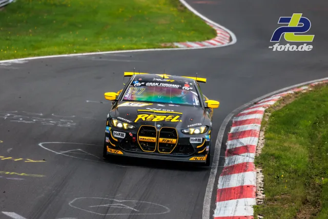 BMW M4 GT3 Nummer 177 in schwarz-gelber Lackierung in einer Kurve der Nürburgring Nordschleife während des NLS-Rennens.