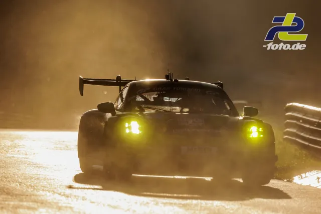 GT3-Rennwagen im Gegenlicht auf dem Nürburgring, gelbe Scheinwerfer leuchten durch Nebel oder Dunst während des Qualifyings.