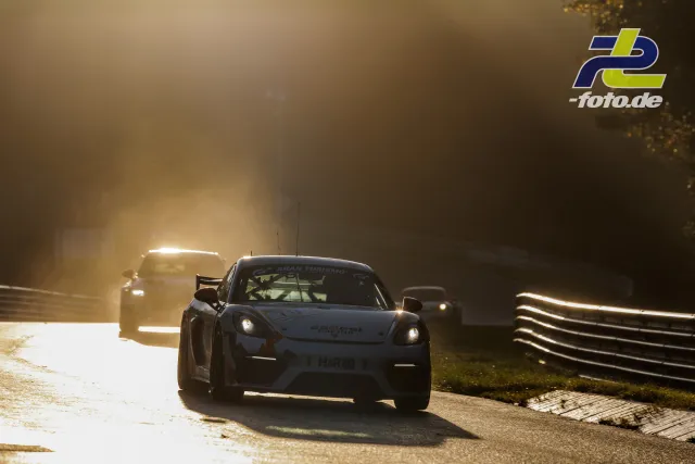 Porsche Cayman GT4 CS im Gegenlicht auf der Nordschleife während des Qualifyings, gefolgt von weiteren Fahrzeugen.