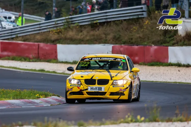BMW mit gelber Lackierung und schwarzen Streifen auf der Nordschleife, Zuschauer hinter der Leitplanke