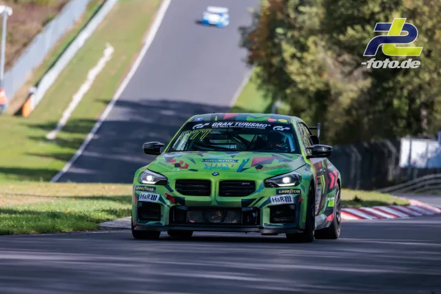 BMW M2 CS Racing mit grüner Lackierung in Kurvensektion der Nordschleife, im Hintergrund weitere Fahrzeuge