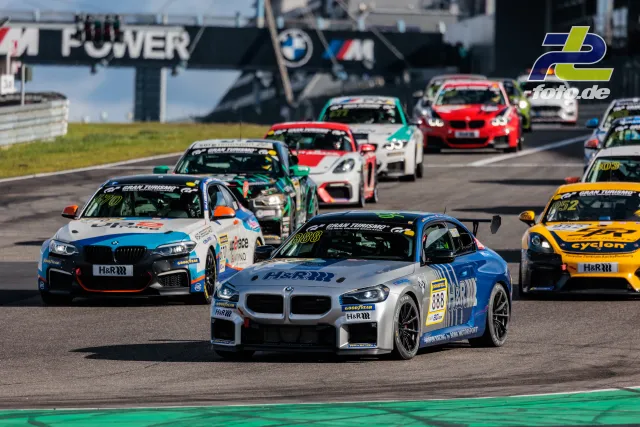 Einführungsrunde beim NLS-Rennen am Nürburgring, Fahrzeugfeld fährt über die Start-Ziel-Gerade mit BMW-Brücke im Hintergrund
