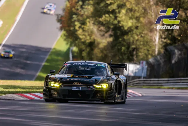 Audi R8 LMS GT3 mit gelben Scheinwerfern im Rennen auf dem Nürburgring, zwei Verfolger im Hintergrund