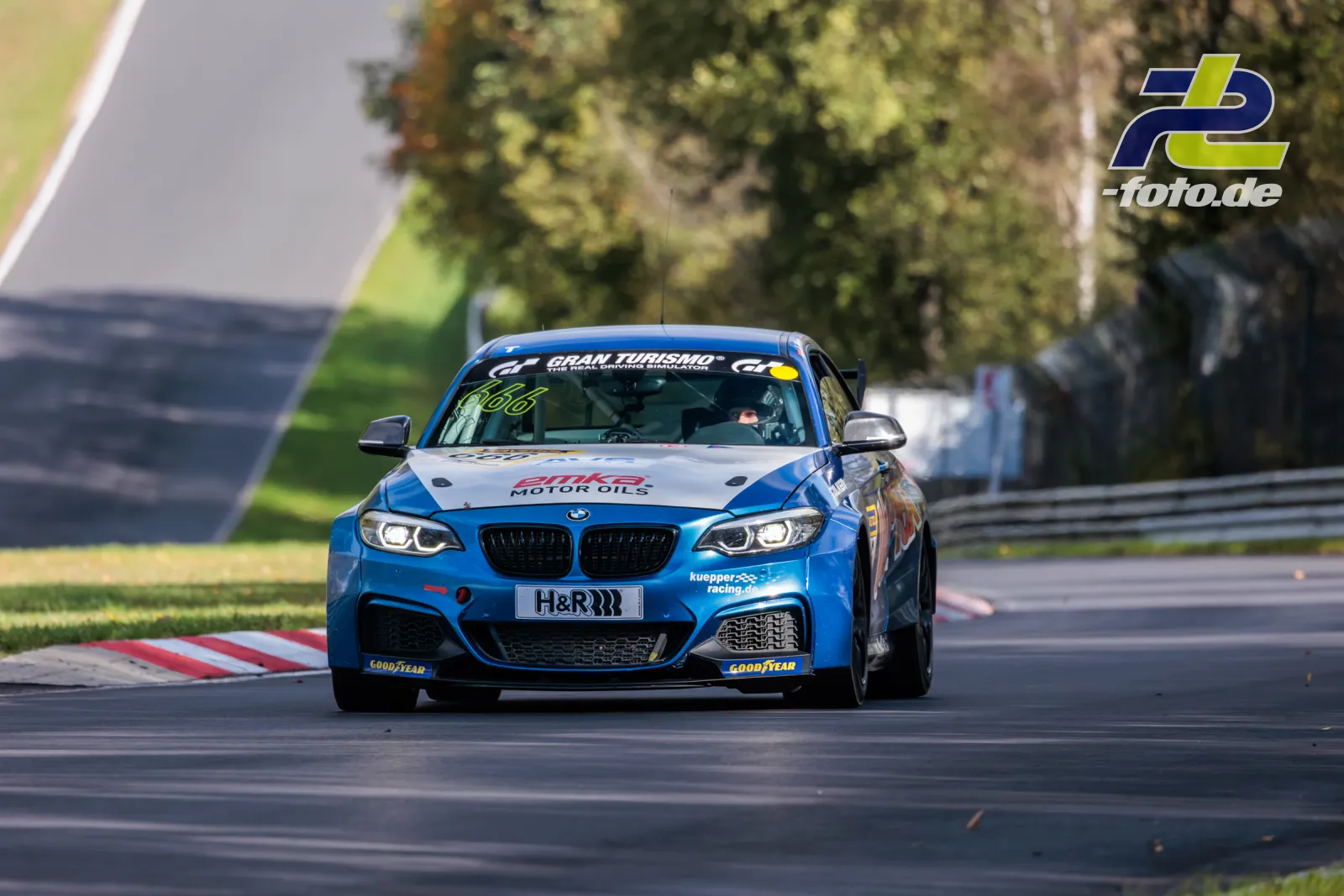 Blauer BMW M240i Racing auf der Nordschleife während des Rennens, gefolgt von einem weiteren Fahrzeug.