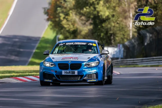 Blauer BMW M240i Racing auf der Nordschleife während des Rennens, gefolgt von einem weiteren Fahrzeug.
