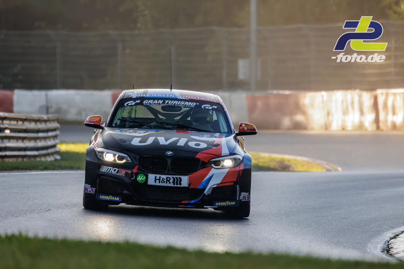 BMW in schwarz-rot-weißer UVIO-Lackierung im Qualifying der NLS am Nürburgring, Frontalansicht in einer Kurve bei Tageslicht.