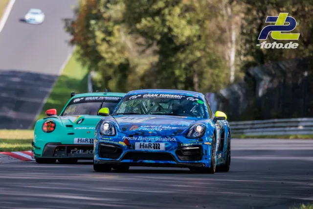 Zwei Porsche Cayman während des Rennens auf dem Nürburgring, vorne ein blau lackierter Wagen mit Werbung für Porsche Zentrum Osnabrück.