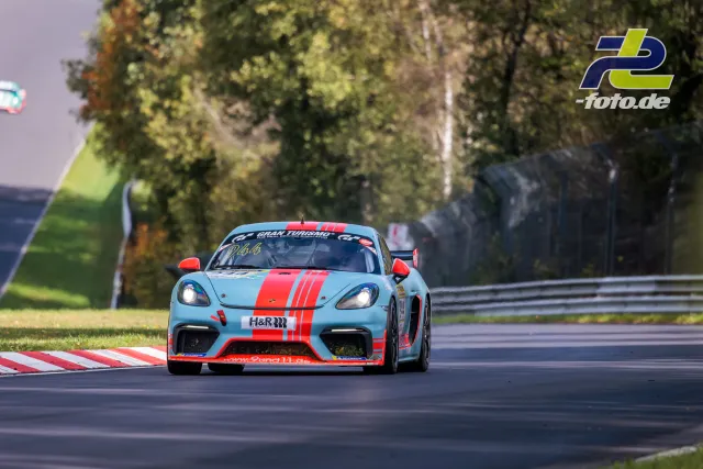 Porsche 718 Cayman GT4 CS in hellblau mit roten Streifen auf der Nürburgring-Nordschleife während des NLS-Rennens im Herbst