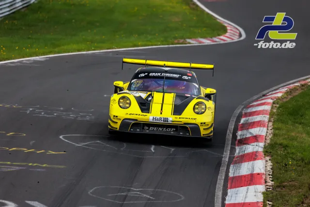 Gelber Porsche 911 GT3-Rennwagen mit schwarzen Streifen auf der Nordschleife des Nürburgrings in einer Kurve.