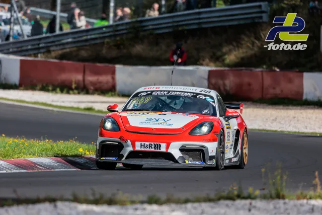 Porsche 718 Cayman GT4 in rot-weißer Lackierung in der Kurve auf der Nürburgring-Nordschleife mit Zuschauern im Hintergrund
