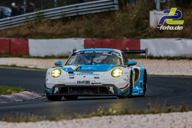 Porsche 911 GT3 R in weiß-blauer Lackierung auf der Nordschleife während eines NLS-Rennens am Nürburgring.