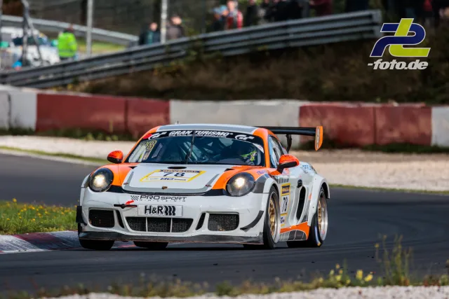 Porsche 911 GT3 R in weiß-orange beim Rennen auf dem Nürburgring, Licht an, Kurvenausgang
