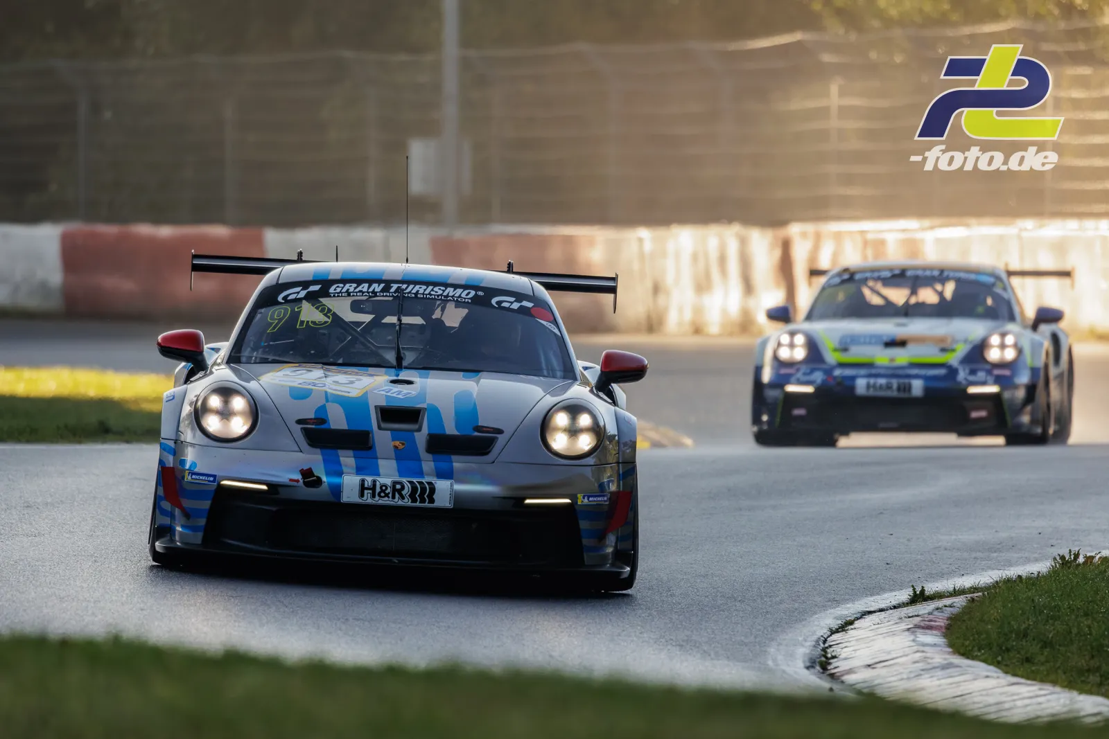 Porsche 911 GT3 Cup Nr. 913 in Kurve während Qualifying am Nürburgring, gefolgt von weiterem Fahrzeug, Frontansicht mit Scheinwerfern.