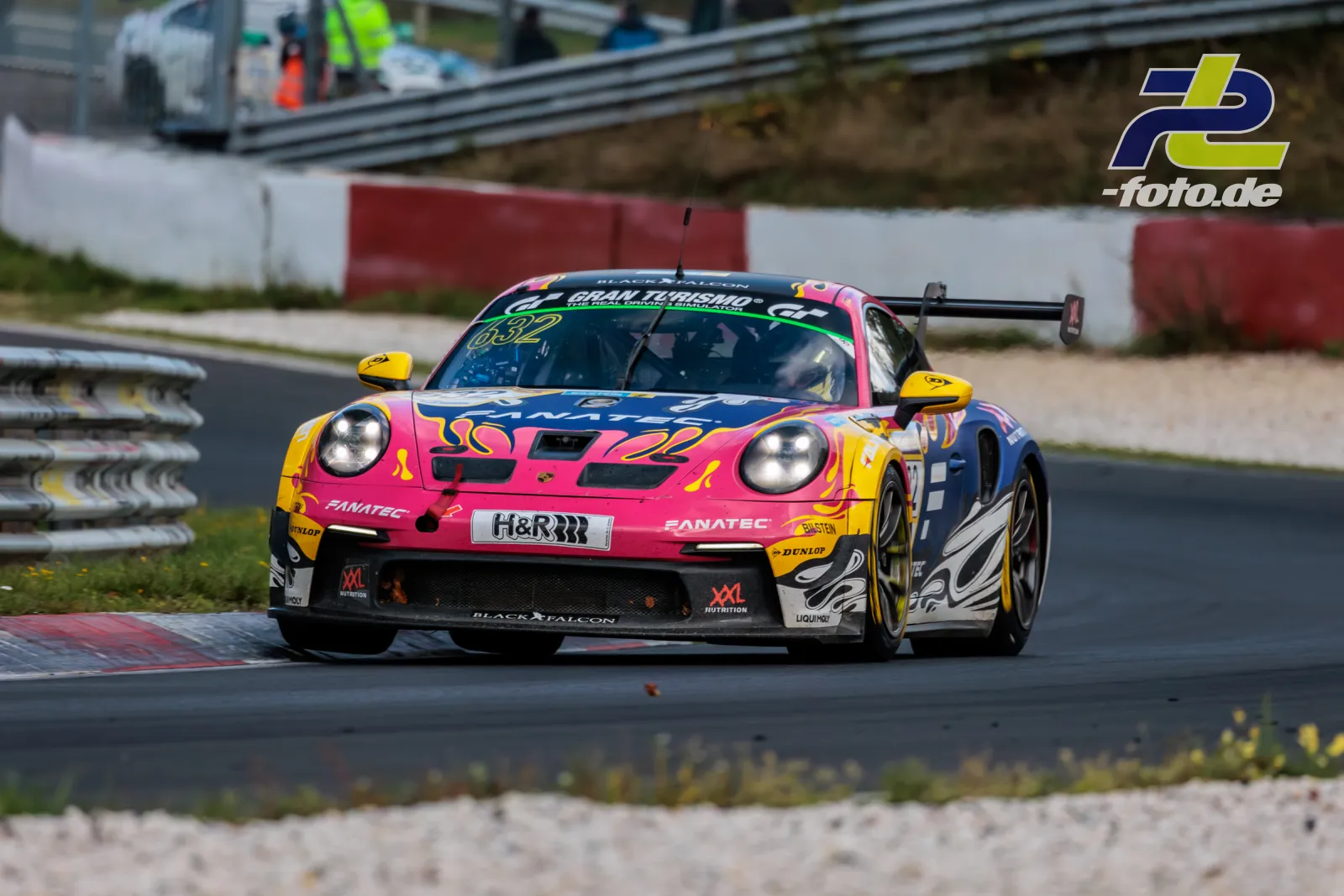Porsche 911 GT3 R #632 in pink-blau-gelber Lackierung fährt auf dem Nürburgring während des NLS-Rennens über den Randstein.