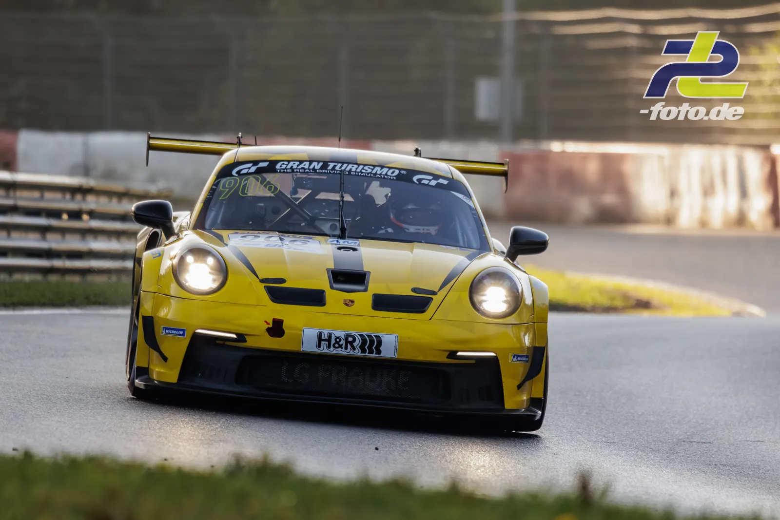 Gelber Porsche 911 GT3 Cup #906 frontal im Qualifying der NLS Sportwarte-Trophy am Nürburgring mit eingeschalteten Scheinwerfern.