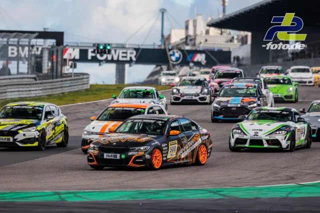Rennfeld auf dem Nürburgring kurz nach dem Start, Startnummer 500 BMW in schwarz-orange führt das Feld an.