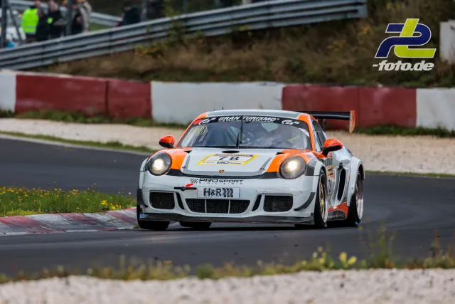Porsche 911 GT3 Nummer 78 in weiß-oranger Lackierung bei der NLS Sportwarte-Trophy auf dem Nürburgring in der Kurve.