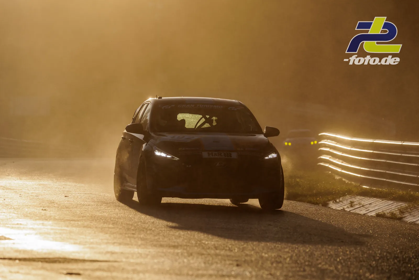 Rennfahrzeug in Frontalansicht bei Gegenlicht auf der Nordschleife, zweites Fahrzeug im Hintergrund während des Qualifyings