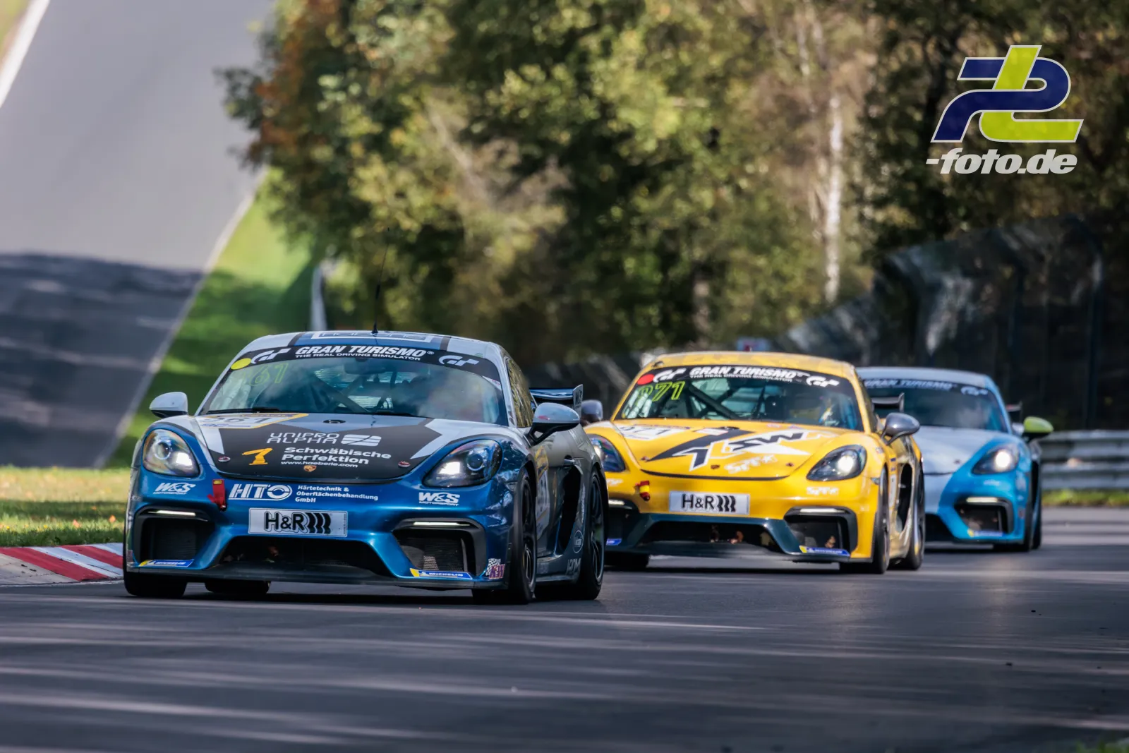 Drei Porsche 718 Cayman GT4 im Renngeschehen auf dem Nürburgring während des NLS-Rennens.